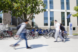 students walking by bike rack on campus
